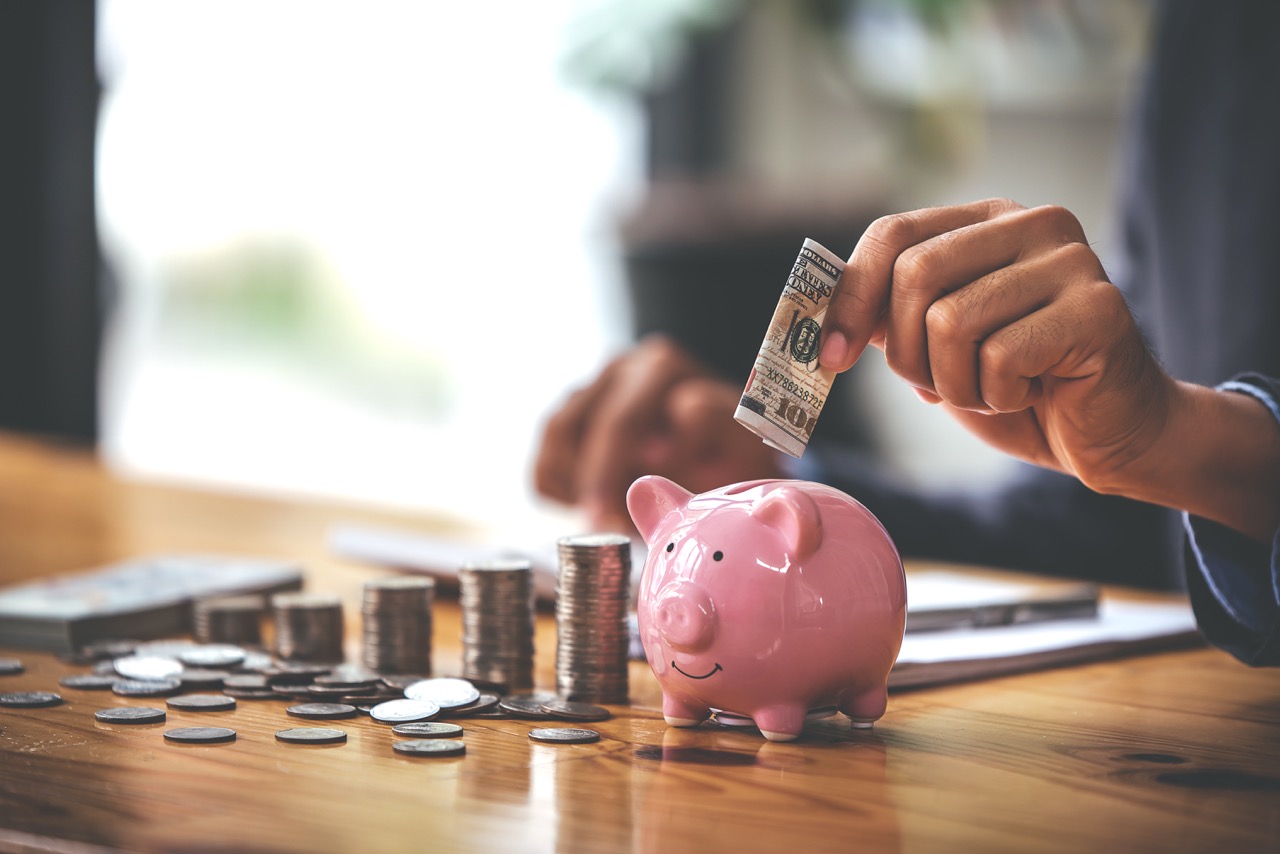 businessman-holding-a-coin-in-a-piggy-bank-on-a-ta-2025-03-09-21-49-23-utc Duży